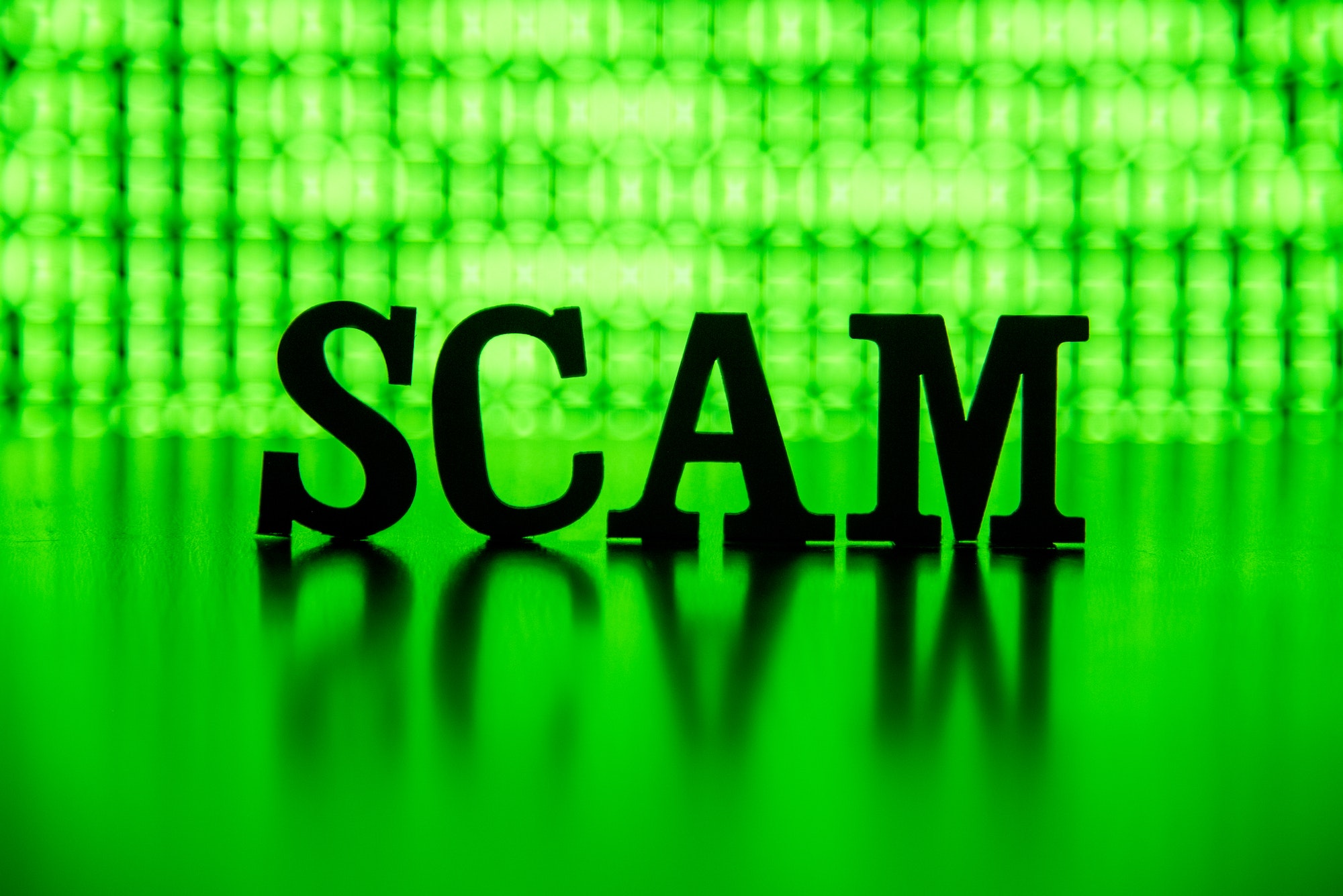 SCAM spelled out backlit by green